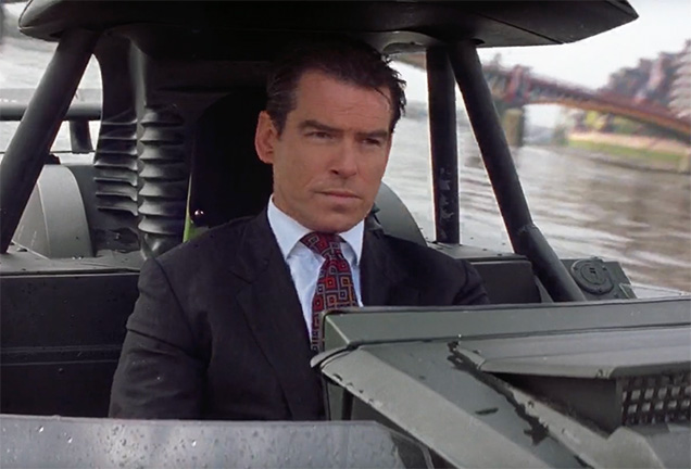 photo © EON, Danjaq LLC, MGM, United Pictures In The World Is Not Enough, Pierce Brosnan as James Bond wears a dark grey Turnbull & Asser tie with grey, tan and burnt orange square motif.