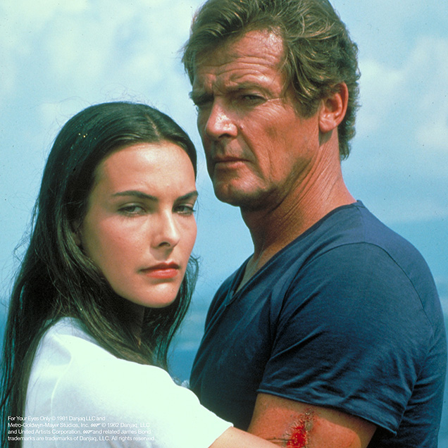 photo © Danjaq LLC, Metro-Goldwyn-Mayer Studios, Inc Roger Moore as James Bond in For Your Eyes Only wearing a blue v-neck t-shirt and white shorts, just before he and Melina Havelock are thrown int the sea